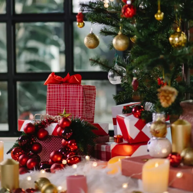 Christmas gifts and indoor Christmas tree with candles and fake snow